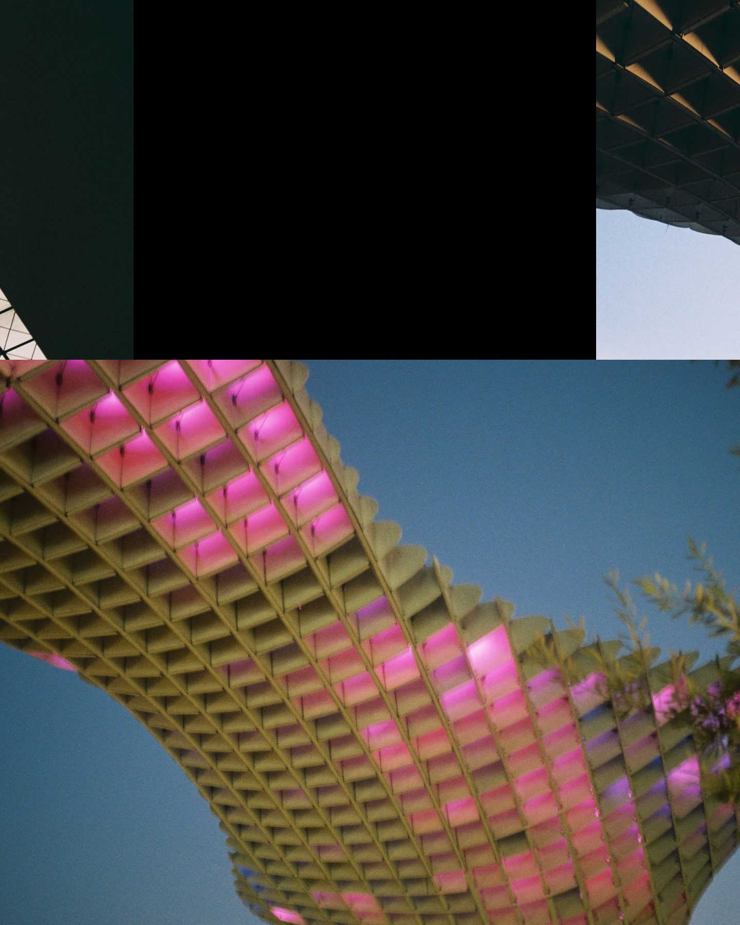 Slide 2 of 3: the underside of a wooden lattice canopy glowing pink against a blue sky